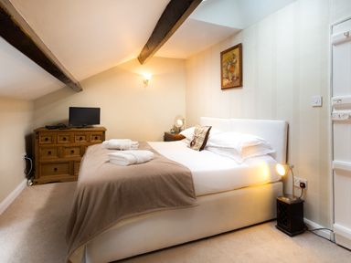 A bedroom with a bed covered with towels a wooden chest of drawers and a small TV at Ghyll Foot Cottage Ambleside