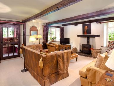 A living room with sofas a wood burning stove and a television at Fair Rigg Old Farm in Cartmel