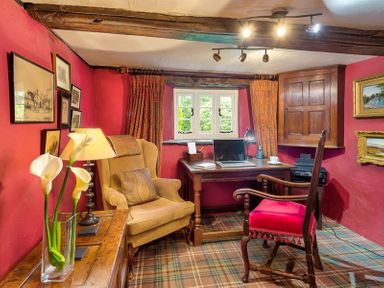 A study room with a wooden desk a laptop a beige armchair and a wooden chair with red seat at Fair Rigg Old Farm in Cartmel