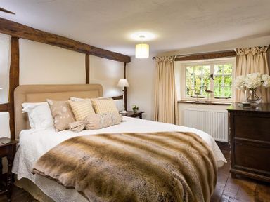A bedroom with a large bed pillows bedside tables lamp window and curtains at Fair Rigg Old Farm in Cartmel