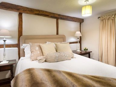 A bedroom with a bed lamps two bedside tables and curtains at Fair Rigg Old Farm in Cartmel