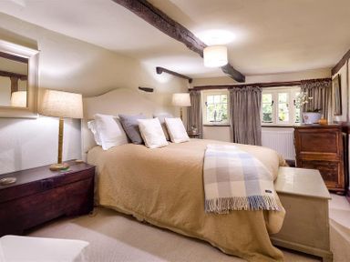 A bedroom with a large bed lamps and wooden furniture at Fair Rigg Old Farm in Cartmel