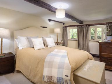 A bedroom with a bed lamps and windows at Fair Rigg Old Farm in Cartmel
