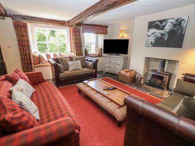 A living room with sofas a wooden coffee table a fireplace and a television at Low Cartmell Fold in Crosthwaite