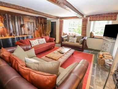 A living room with leather and fabric sofas wooden coffee table red rug and television at Low Cartmell Fold in Crosthwaite