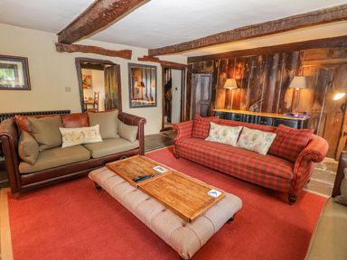 A living room with two sofas a wooden coffee table and exposed wooden beams on the ceiling at Low Cartmell Fold in Crosthwaite