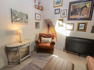 A corner of a living room with a leather armchair and a table with a lamp at Low Cartmell Fold in Crosthwaite