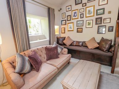 A living room with two sofas a wooden table and framed pictures on the wall at Low Cartmell Fold in Crosthwaite