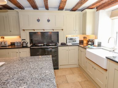 A kitchen with cream cabinets a black stove a microwave and a farmhouse sink at Low Cartmell Fold in Crosthwaite