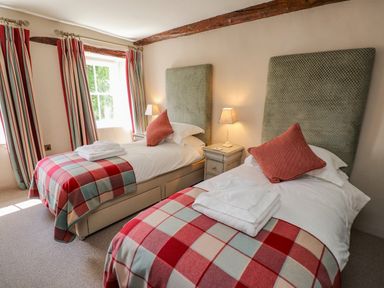 A bedroom with two single beds with plaid blankets and pillows at Low Cartmell Fold in Crosthwaite