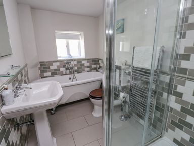 A bathroom with a bathtub a pedestal sink a toilet and a glass shower enclosure at Low Cartmell Fold in Crosthwaite