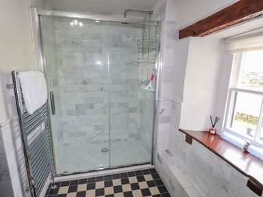 A bathroom with a glass shower enclosure towel rack and a window at Low Cartmell Fold in Crosthwaite
