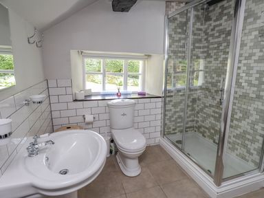 A bathroom with a sink, toilet, and glass shower enclosure with tiled walls at Low Cartmell Fold in Crosthwaite
