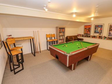 A game room with a pool table chairs bookshelf and framed movie posters at Low Cartmell Fold in Crosthwaite