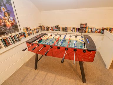 A game room with a foosball table surrounded by bookshelves and a Star Wars Return of the Jedi poster at Low Cartmell Fold in Crosthwaite