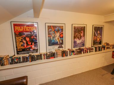 A room with four framed movie posters and a long shelf filled with books at Low Cartmell Fold in Crosthwaite