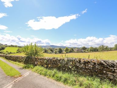 A countryside view with a stone wall and grassy fields at Low Cartmell Fold in Crosthwaite