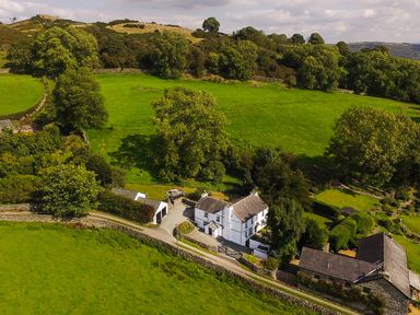 A countryside property with white houses surrounded by green fields and trees at Low Cartmell Fold in Crosthwaite