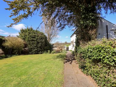 A garden with a lawn path and bushes next to a white building at Low Cartmell Fold in Crosthwaite