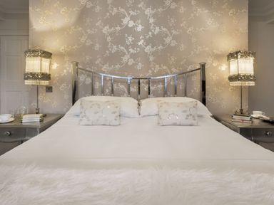 A bedroom with a bed with metallic headboard two pillows and bedside tables with lamps at Tent Lodge in Coniston