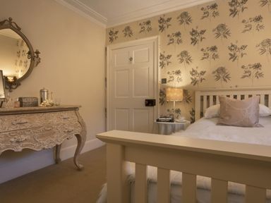 A bedroom with a bed side table lamp pillow and dresser with mirror at Tent Lodge in Coniston