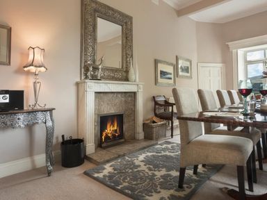 A dining room with a fireplace chairs and a table set with wine glasses at Tent Lodge in Coniston