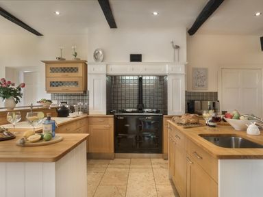 A kitchen with wooden countertops a black stove and kitchen cabinets at Tent Lodge in Coniston