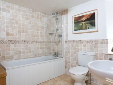 A bathroom with a bathtub shower combination toilet and sink at Pollys Cottage in Langdale