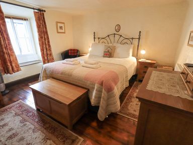 A bedroom with a bed a wooden chest and a window at Springwell Cottage in Ambleside