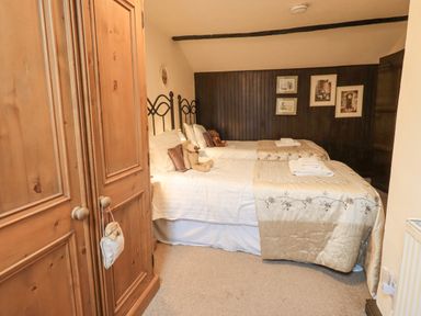 A bedroom with two single beds with teddy bears and a wooden wardrobe at Springwell Cottage in Ambleside