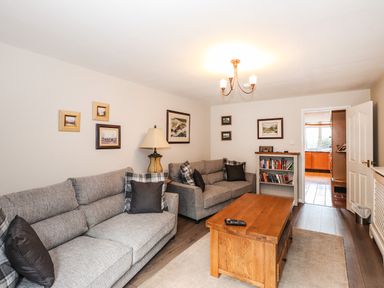 A living room with two grey sofas a wooden coffee table and framed pictures on the wall at Candleberry Cottage in Ambleside