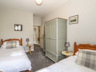 A bedroom with two single beds a large wardrobe two bedside tables and two lamps at Candleberry Cottage in Ambleside