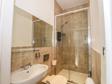 A bathroom with a sink toilet and glass shower enclosure with tiled walls at Candleberry Cottage in Ambleside