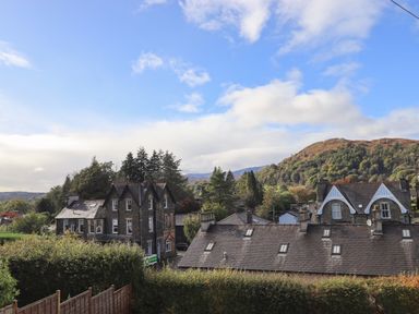View of residential houses with trees and hills in the background in Ambleside