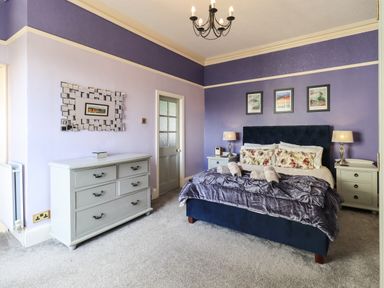 A bedroom with a bed flanked by two nightstands with lamps a dresser and three pictures on the wall at Gale Lodge Cottage in Ambleside