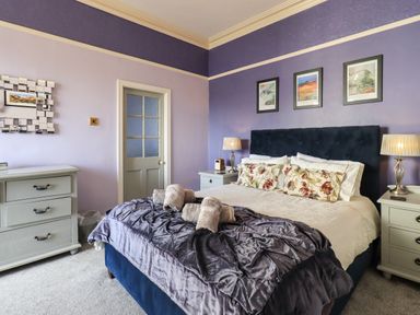 A bedroom with a double bed pillows and towels bedside tables with lamps a chest of drawers and a door at Gale Lodge Cottage Ambleside