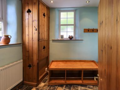 A small room with wooden storage cabinets a wooden bench and two windows with frosted glass at Gale Lodge Cottage in Ambleside