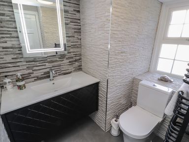 A bathroom with a sink and mirror and a toilet next to a window at Gale Lodge Cottage in Ambleside