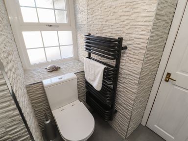 A bathroom with a toilet black towel radiator and a window at Gale Lodge Cottage in Ambleside