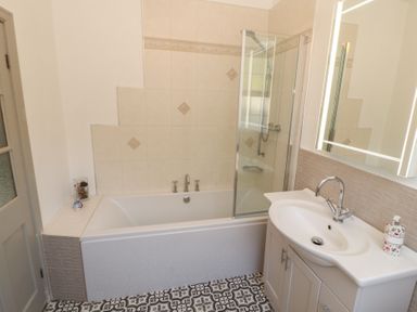A bathroom with a bathtub shower combination and a sink with a mirror at Gale Lodge Cottage in Ambleside