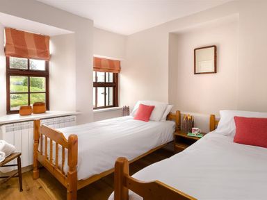 A bedroom with two single wooden beds and windows with orange blinds at Barn Cottage in Bassenthwaite near Keswick