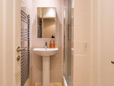 A small bathroom with a pedestal sink mirror and glass shower door at Barn Cottage Bassenthwaite near Keswick