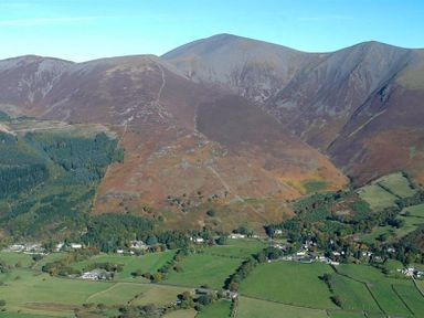 Mountains with vegetation and a small village with fields at the base