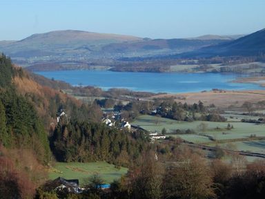 A landscape with a lake surrounded by hills trees and houses at Barn Cottage in Bassenthwaite near Keswick