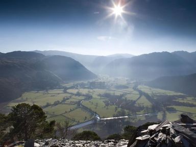 A valley with segmented fields and a river surrounded by hills under the sun at Barn Cottage in Bassenthwaite near Keswick