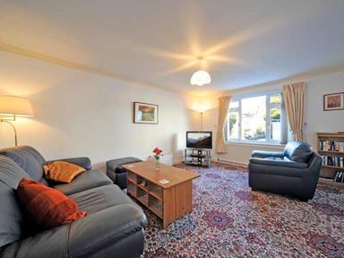 A living room with sofas coffee table television and a bookshelf at Mosslea in Bowness