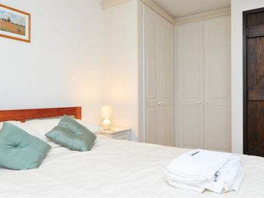 A bedroom with a bed two green pillows a bedside table with a lamp a wardrobe and a folded towel on the bed at Mosslea in Bowness