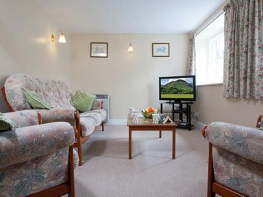 A living room with sofas a wooden coffee table and a television at Low Croft Cottage in Grasmere