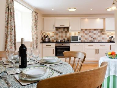 A kitchen with a dining table set with plates glasses and a wine bottle at Low Croft Cottage in Grasmere