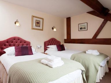 A bedroom with two single beds green blankets and red headboards at Low Croft Cottage in Grasmere